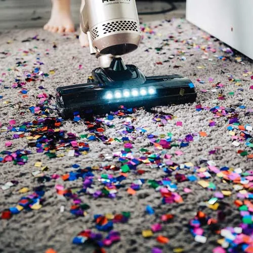 Person vacuuming confetti of carpet